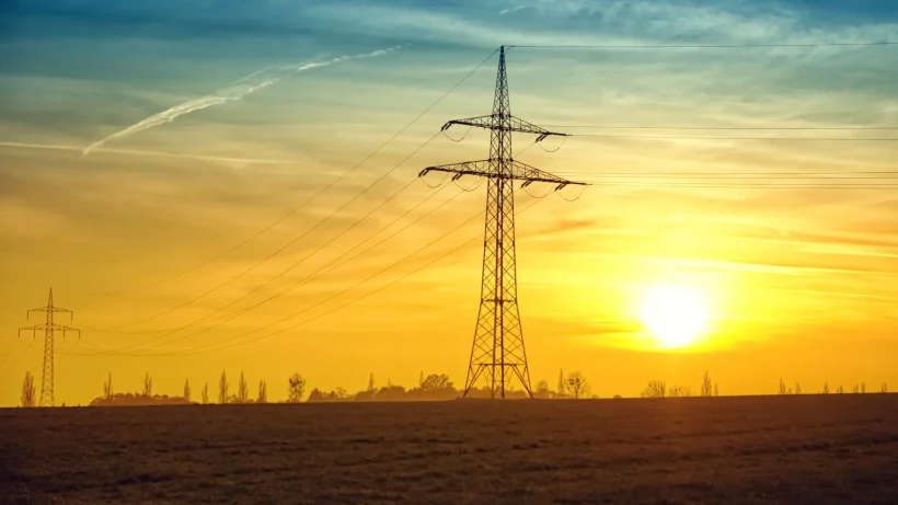 The sun setting over power lines used to illustrate Ofgems Announcement of a New Energy Price Cap From October 2023